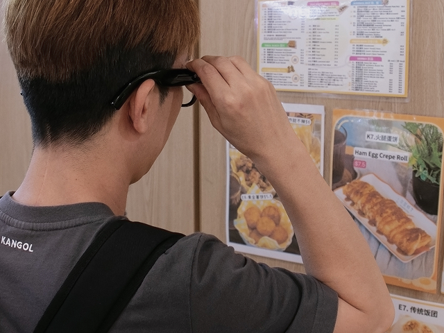 A man using AiSee glasses to read the menu display.